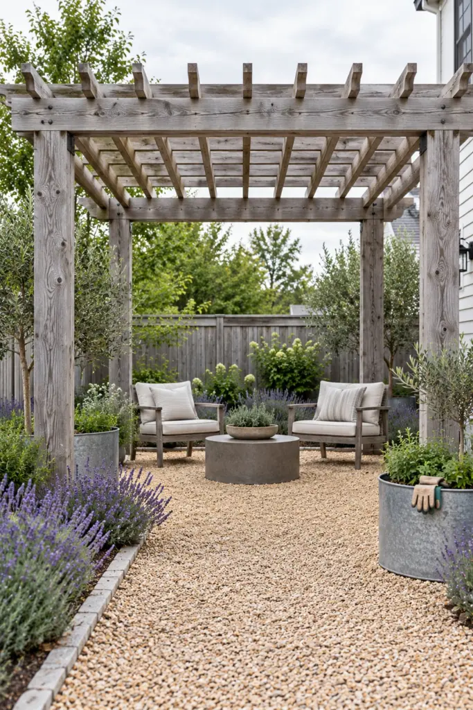 Bare cedar pergola weathered silver-gray over a pea gravel patio with lavender and steel planters